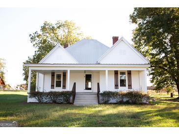 White farmhouse with a front porch, landscaping, and large yard at 10 Maranatha Rd, Mcdonough, GA 30252