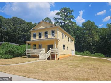 Two-story yellow house with a front porch and landscaped yard at 321 Seventh Ave, Scottdale, GA 30079