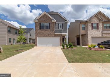 Two-story brick home with a two-car garage and landscaped lawn at 1705 Labonte Pkwy, Mcdonough, GA 30253