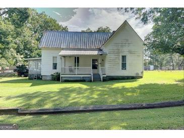Charming white farmhouse with a wraparound porch at 27 Smith St, Locust Grove, GA 30248