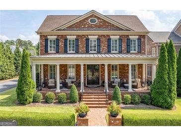 Brick two-story home with a large front porch and landscaped yard at 8025 Georgetown Cir, Suwanee, GA 30024