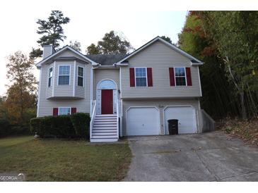 Tan two-story house with red door and attached two-car garage at 6995 Pine Shadow Way, Winston, GA 30187