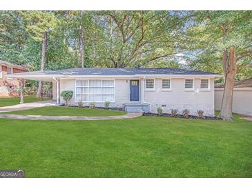 Charming ranch home with a white brick facade, landscaped lawn, and a blue front door at 1370 David Cir, Decatur, GA 30032