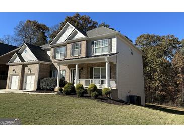 Two-story house with brick and siding, covered porch, and two-car garage at 2536 Kachina Trl, Dacula, GA 30019