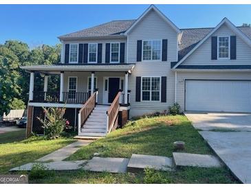 Two-story house with gray siding, a wraparound porch, and a two-car garage at 11684 Heritage Dr, Hampton, GA 30228