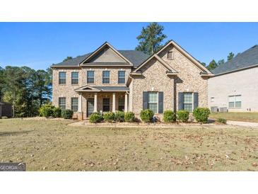 Two-story brick home with a front porch and landscaped yard at 6857 Louis Dr, Locust Grove, GA 30248