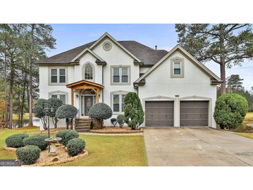 Two-story house with white exterior, landscaping, and a two-car garage at 12021 Scottish Ct, Fayetteville, GA 30215