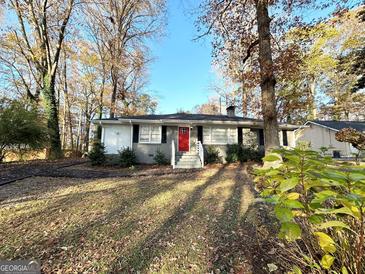 Ranch home with red door, steps, and landscaping at 8406 Norris Lake Rd, Snellville, GA 30039