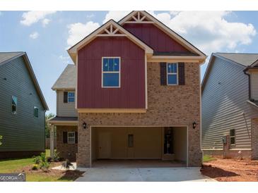 Two-story house with red and brown siding, attached garage, and landscaping at 2275 Lovejoy Rd # 72, Hampton, GA 30228