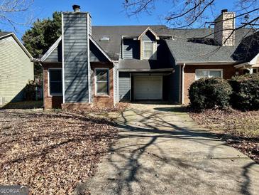Two-story house with gray siding, brick base, and attached garage at 7978 Woodlake Dr, Riverdale, GA 30274