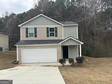 Two-story house with a white garage door and landscaping at 306 Blackfoot Trl, Villa Rica, GA 30180