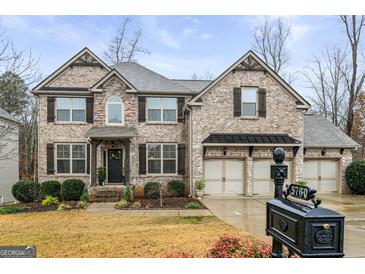 Brick two-story house with three-car garage and landscaped yard at 5760 Winding Lakes Dr, Cumming, GA 30028