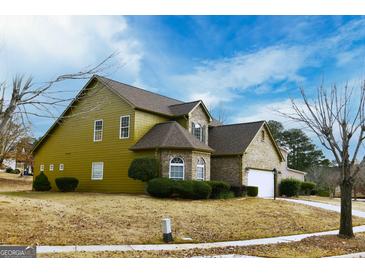 Two-story house with stone and siding, two-car garage, and landscaping at 6383 Edgewater Cv, Fairburn, GA 30213