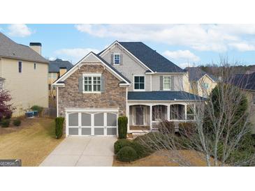 Two-story home with stone and siding exterior, front porch, and attached garage at 4335 Silent Path, Cumming, GA 30028