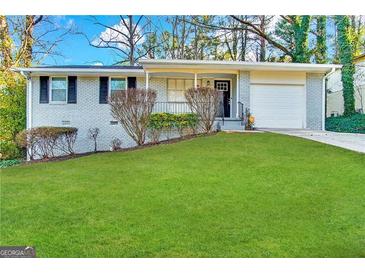 Charming single-story home with a white brick exterior, attached garage, and lush green lawn at 2830 Battle Forrest Dr, Decatur, GA 30034