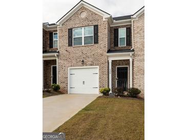 Attractive townhome exterior with a one-car garage and brick facade at 1304 Speckle Park Way, Stockbridge, GA 30281