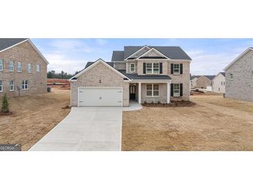 New construction home with brick and siding exterior, front-facing two-car garage, and landscaping at 663 Edgar St # 25, Hampton, GA 30228