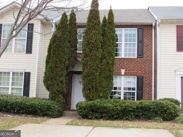 Brick front exterior of townhome with landscaping and two-story design at 2055 Grove Way, Hampton, GA 30228