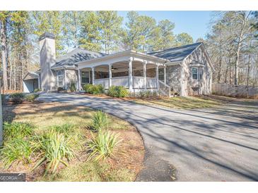 Ranch style home with stone accents, covered porch, and mature trees at 564 Eskew Rd, Mcdonough, GA 30252