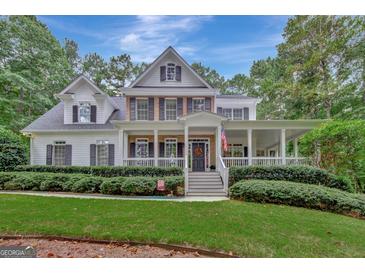 Two-story home with wrap-around porch, lush landscaping, and a brick facade at 100 Dresden Pl, Fayetteville, GA 30215