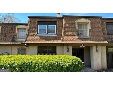 Charming two-story townhome with a brown shingled roof and manicured shrubs at 3000 Parc Lorraine, Lithonia, GA 30038