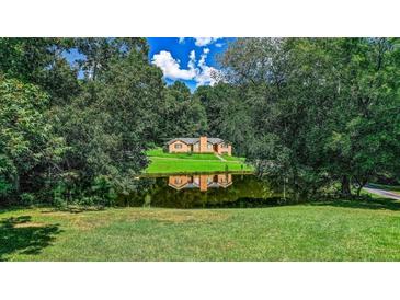 Ranch home nestled on a wooded lot with a pond reflection at 3409 Camp Branch Rd, Buford, GA 30519
