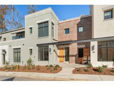 Modern townhome with light gray and brick exterior, wooden front door, and landscaping at 10871 Serenbe Ln, Chattahoochee Hills, GA 30268