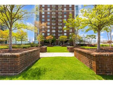 Courtyard with manicured lawn, brick planters, and a view of a modern highrise building at 285 Centennial Olympic Park Nw Dr # 1108, Atlanta, GA 30313