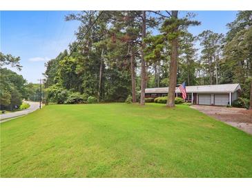 Ranch style home with large yard and mature trees at 881 Rockbridge Sw Rd, Lilburn, GA 30047