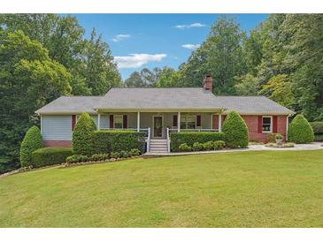 Ranch-style home with covered porch, brick accents, and landscaped yard at 3992 Doc Sams Rd, Cumming, GA 30028