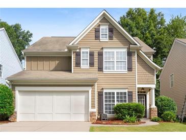Two-story house with tan siding, white garage door, and dark shutters at 320 Pintail Ct, Suwanee, GA 30024