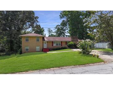 Ranch style house with a red door and nicely landscaped lawn at 8347 Hilltop Rd, Jonesboro, GA 30236
