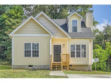 Cute yellow house with gray roof, small front porch, and landscaping at 2259 Sisk Nw St, Atlanta, GA 30318