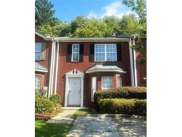 Two story red brick townhouse with landscaping and driveway at 2794 Norfair Loop, Lithonia, GA 30038