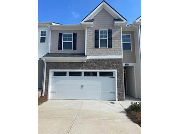 Two-story townhome with gray siding, white garage door, and stone accents at 308 Elgin Dr, Lawrenceville, GA 30045