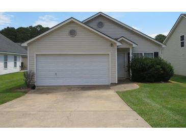 Beige house with a white garage door and well-maintained lawn at 435 Victoria Blvd, Oxford, GA 30054