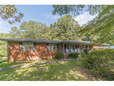 Brick ranch house with front porch, rocking chairs, and mature trees at 1645 Highpoint Rd, Snellville, GA 30078