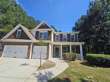 Two story house with brick and wood siding, a two car garage, and a covered porch at 2900 Brandford Trl, Locust Grove, GA 30248