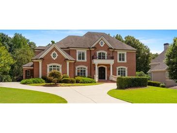 Grand brick home with circular driveway and manicured lawn at 3133 Saint Ives Country Club Pkwy, Johns Creek, GA 30097