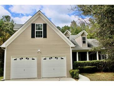Two-story house with beige siding, two-car garage, and landscaping at 7025 Fletcher Dr, Winston, GA 30187
