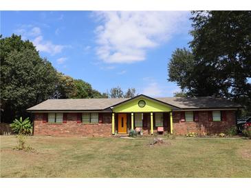 Brick ranch house with a vibrant yellow front at 2696 Eldorado Pl, Snellville, GA 30078