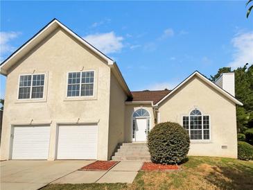 Two-story house with a beige stucco exterior, two-car garage, and landscaping at 277 Players Cir, Fayetteville, GA 30215