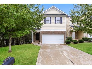 Two-story townhome with a beige exterior, two-car garage, and well-manicured lawn at 6393 Shadow Sq, Lithonia, GA 30058