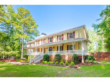 Two-story yellow house with large porch and yard at 3060 Orchard Sw Rd, Conyers, GA 30094