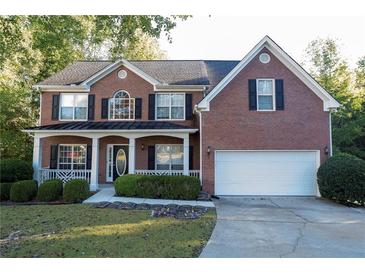 Brick two-story house with a white garage door and landscaping at 994 Rolling Forest Ln, Lilburn, GA 30047
