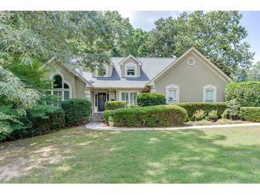 Tan house with gray roof, manicured lawn, and lush landscaping at 2000 Shadwell Way, Lawrenceville, GA 30043