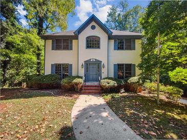 Two-story house with white brick exterior, gray shutters, and a landscaped yard at 709 Tribal Trl, Woodstock, GA 30188