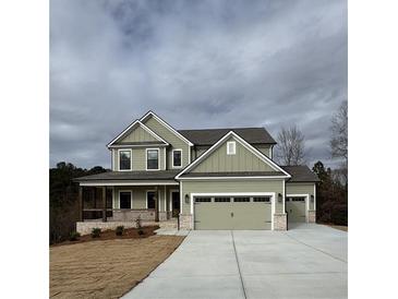 Charming two-story home with a covered front porch, three-car garage, and landscaped yard at 1129 Red Oak Blvd, Loganville, GA 30052