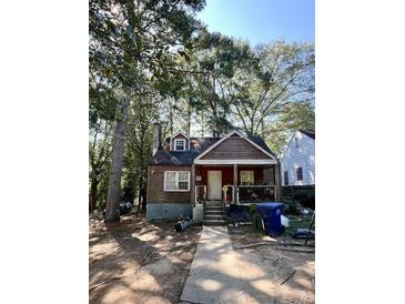 Ranch style home with wood siding and a covered porch, nestled among tall trees at 1876 Madrona Nw St, Atlanta, GA 30318