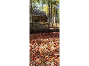 Autumn leaves blanket the ground, showcasing a house nestled in the woods at 613 Rock Springs Pass, Dallas, GA 30157